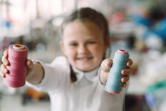 Little girl standing in the factory with a thread