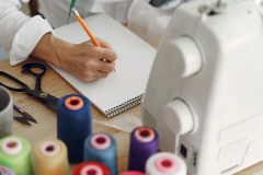 Woman sitting in studio and sew cloth